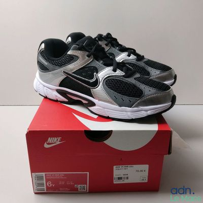 une paire de chaussures noires et argentées posée sur une boîte rouge