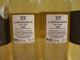 three bottles of white wine are lined up on a table