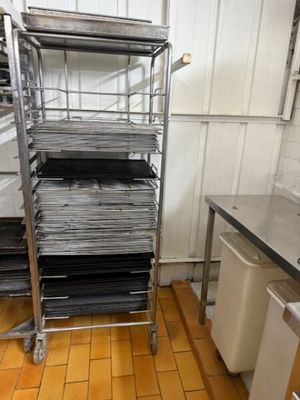 une étagère métallique sur laquelle sont posés plusieurs plateaux, dans une cuisine