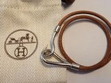 un petit sac muni d'une bandoulière en cuir marron et d'un fermoir argenté