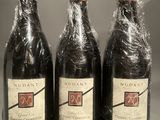 three bottles of wine wrapped in plastic on a table