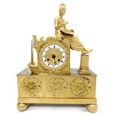 une horloge en or avec une femme assise dessus