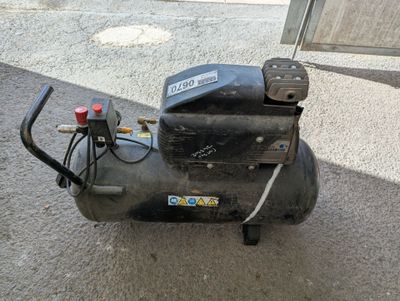 a black air compressor sitting on the ground next to a building