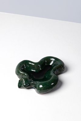 un petit objet vert posé sur une surface blanche