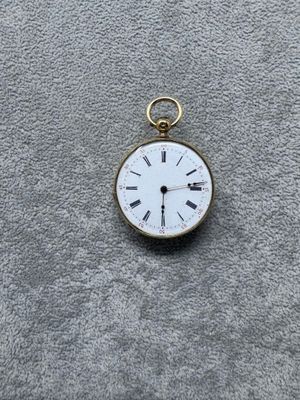 une petite montre de poche en or avec des chiffres romains