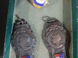two watches in a display case with badges on them