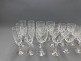 twelve wine glasses lined up in a row on a gray surface