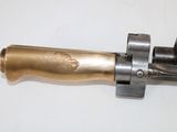 a metal object with a metal handle on a white surface