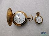 a gold pocket watch and a gold pocket watch on a white surface