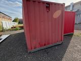 a red container sitting on the ground in front of a building