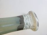 a green vase with a white base on a table