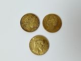 three gold coins sitting on top of each other on a white surface