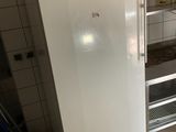 a white refrigerator in a kitchen with a shelf on the wall