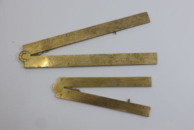 three brass rulers on a white surface with a ruler in the middle