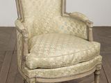 une vieille chaise dont l'assise est recouverte d'un tissu à motifs, posée sur un parquet