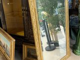 un grand miroir posé sur une table, à côté d'un vase