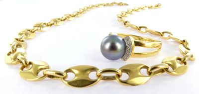 a close up of a gold chain bracelet with a black pearl