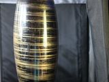 un vase noir et doré posé sur un canapé noir