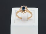 gros plan d'une bague en or avec un saphir et des diamants