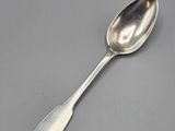 silver spoon with a long handle sitting on a gray surface