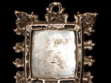 an image of a silver pendant with skulls and flowers on it