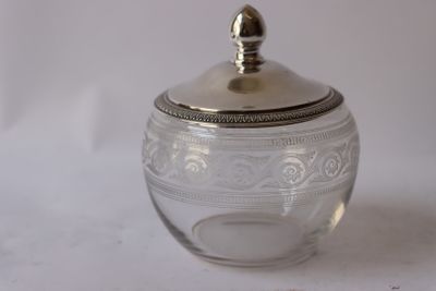 a glass jar with a silver lid on a white surface