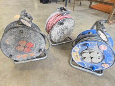 three hose reels sitting on top of a cement floor next to each other