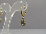 gold plated earrings with blue stones on a clear acrylic stand