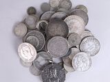 un tas d'argent et de pièces d'argent posé sur une surface blanche