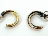 two pairs of silver and gold earrings on a white surface