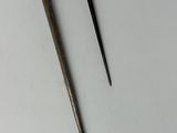 two metal tools sitting on top of a white surface next to each other