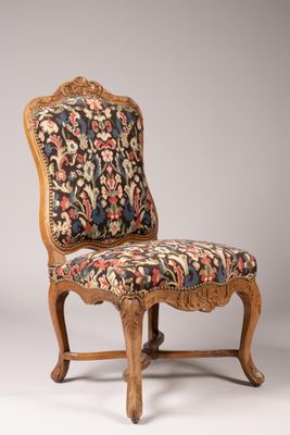 une chaise dont le dossier est recouvert d'un tissu à motifs floraux et dont la structure est en bois