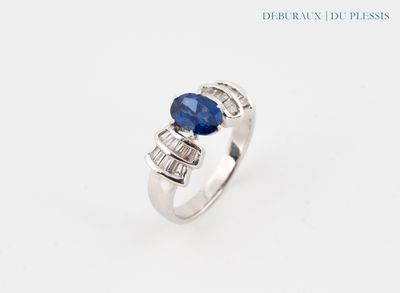 une bague en or blanc sertie d'un saphir bleu et de saphirs taille baguette