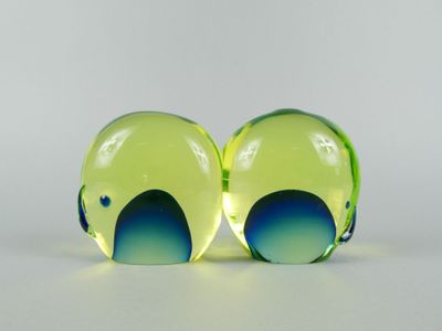 two yellow and blue glass spheres sitting on top of a white surface