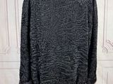 the back of a black jacket on a hanger in front of a white wall