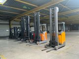 Plusieurs chariots élévateurs sont garés dans un grand entrepôt, avec un garage en arrière-plan.