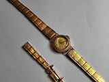 a gold watch and a gold bracelet on a white surface