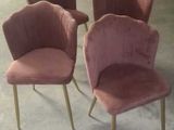 four pink velvet chairs in a warehouse with a white wall in the background