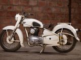 a white motorcycle that is parked in front of a brick wall