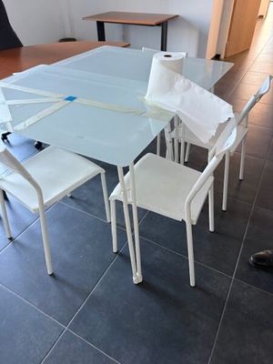 une table en verre avec des chaises blanches et une chaise blanche