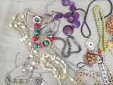 many necklaces and bracelets laid out on a table