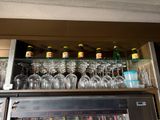 many wine glasses on a shelf above a microwave