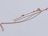 gros plan d'un collier en or avec une chaîne sur fond blanc
