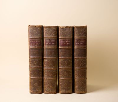 trois vieux livres posés l'un sur l'autre sur une surface blanche