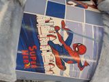 a stuffed animal holding a book with a picture of a spider - man on it