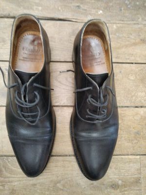 une paire de chaussures en cuir noir à lacets posée sur un parquet