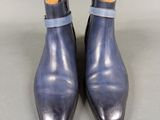 a pair of blue leather ankle boots on a grey surface