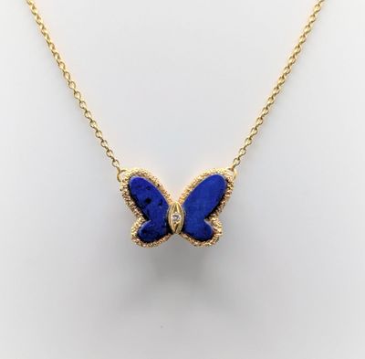 a gold necklace with a blue butterfly pendant on it