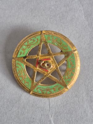 un pentagramme doré et vert surmonté d'une étoile
