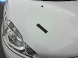 the front end of a white car with a sticker on it